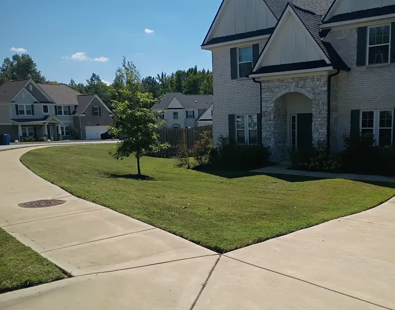 Corner-lot lawn with mowing stripes and sharp edges along the sidewalk